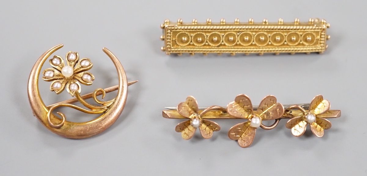 A late Victorian 15ct and seed pearl set flower and crescent brooch, 22mm, gross 3.1 grams and two later yellow metal bar brooches, gross 6 grams.